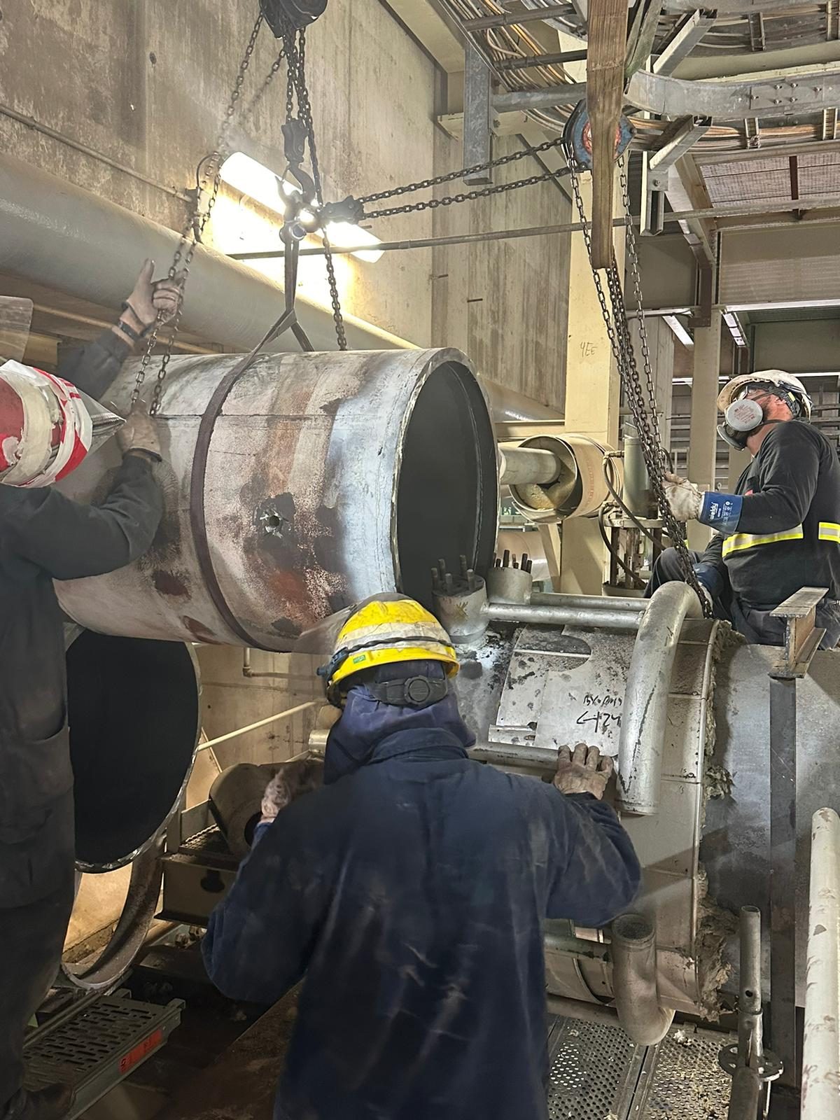 Operarios con casco durante el mantenimiento de un equipo industrial